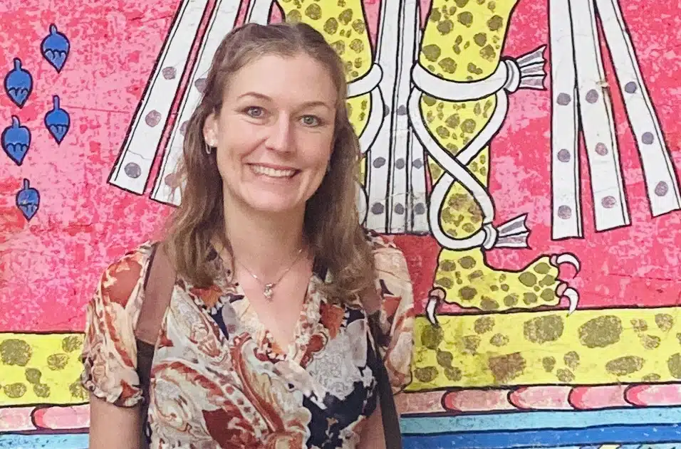 Photo of Annie Bergen in front of colourful pink and yellow mural