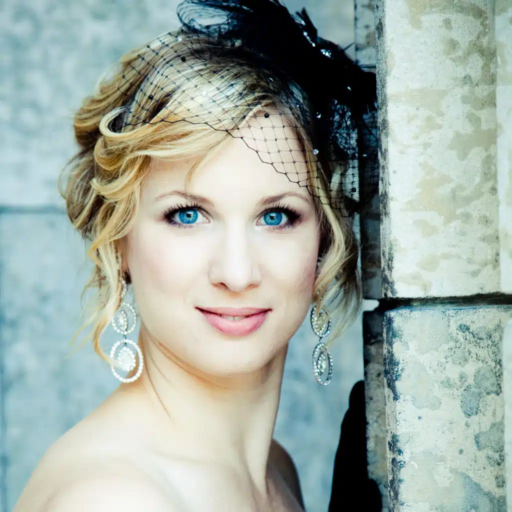 Woman with netted fascinator facing camera