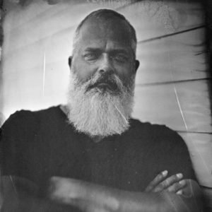 Black and white photo of bearded man with arms folded